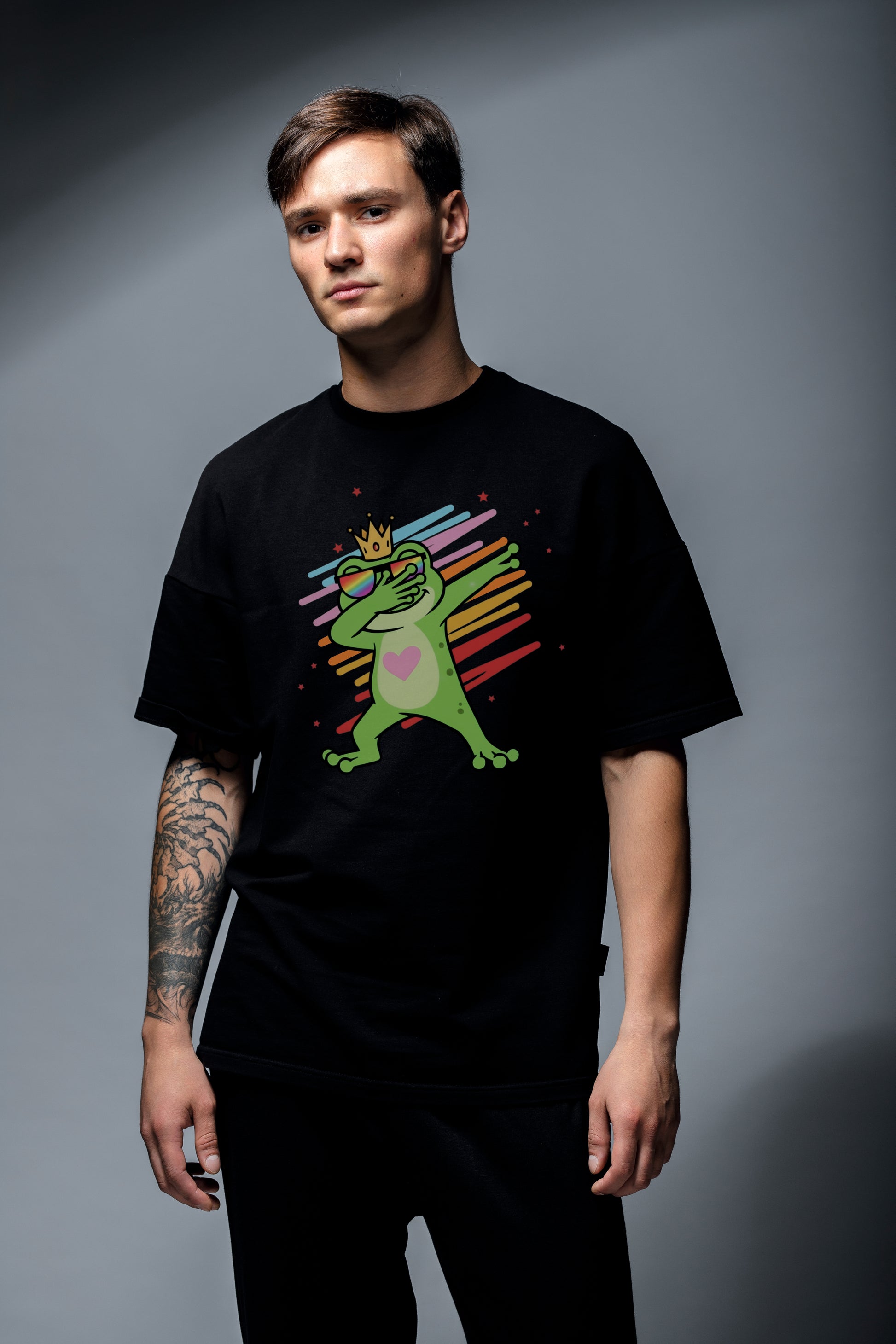 „Schwarzes Herren‑T‑Shirt mit bunter Cartoon‑Grafik eines dabenden Froschs mit Krone und Sonnenbrille vor Regenbogenlinien.“