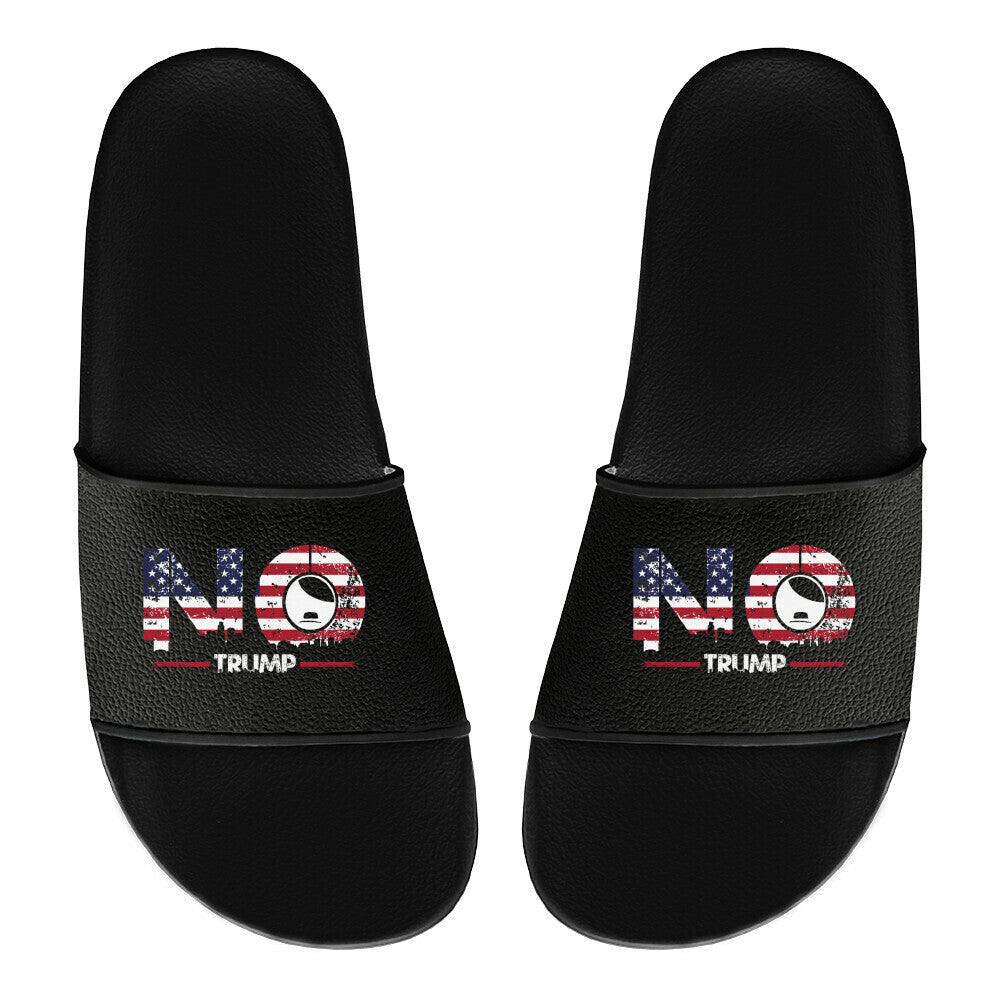 Schwarze Statement-Sandalen mit „NO TRUMP“-Print, US-Flaggenmuster und stilisiertem Masken-Symbol – klare politische Botschaft gegen Rechtspopulismus, kombiniert mit modernem Design.