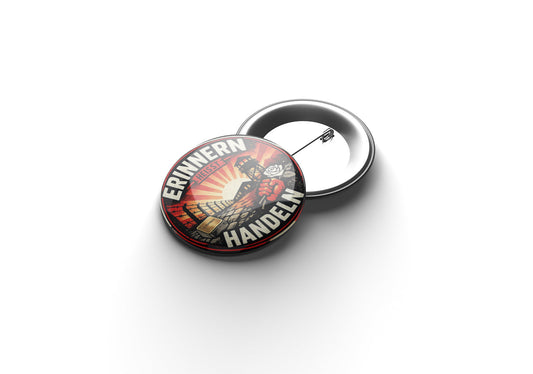 „Runder Button mit gelbem Hintergrund und stilisierter Darstellung eines Lagergeländes mit Wachturm und Stacheldraht; im Vordergrund eine rote Faust, die eine weiße Rose hält, daneben ein Gedenkstein mit der Aufschrift ‚Never Forget‘; am Rand steht in weißer Schrift ‚Erinnern heißt Handeln‘.“