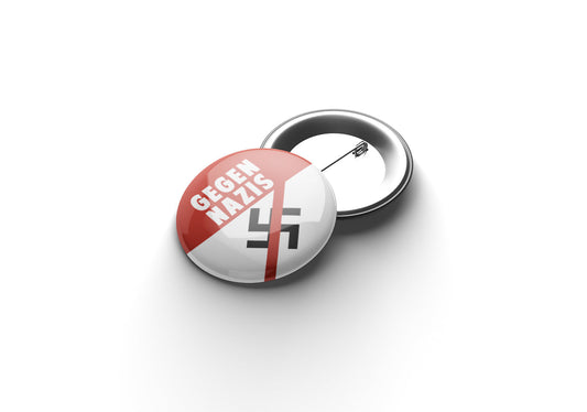 „Runder Button mit rotem oberen Bereich und weißer Aufschrift ‚GEGEN NAZIS‘; im unteren weißen Bereich befindet sich ein durchgestrichenes schwarzes Symbol, das eine klare Anti‑Nazi‑Botschaft ausdrückt.“