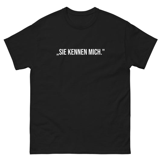 "Schwarzes T-Shirt mit dem weißen Zitat von Angela Merkel 'SIE KENNEN MICH.' auf der Vorderseite. Teil der exklusiven 'Die Raute' Comeback-Serie."

