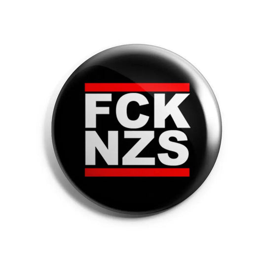 „Runder Button mit der Aufschrift ‚FCK NZS‘ in weißer Blockschrift auf rotem Hintergrund.“