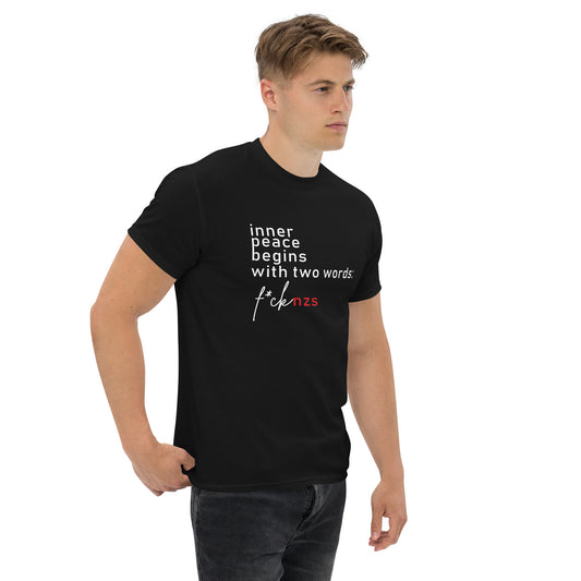 Schwarzes Unisex T‑Shirt mit weiß‑rotem Print: ‚Inner Peace Begins With Two Words: FCK NZS‘, getragen von Person in entspannter Haltung.